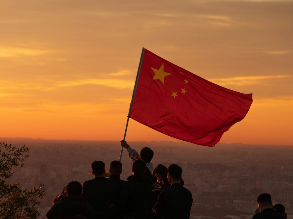 Group of people flying the national flag of China amid adoption of the MCP standard for more capable AI agents.