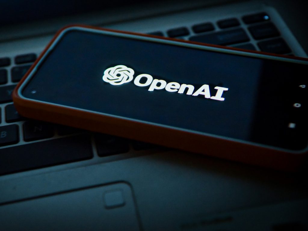 Close-up of the OpenAI logo on a mobile device as a coalition of experts, including former OpenAI employees, has voiced strong opposition to the company's shift away from its nonprofit roots.